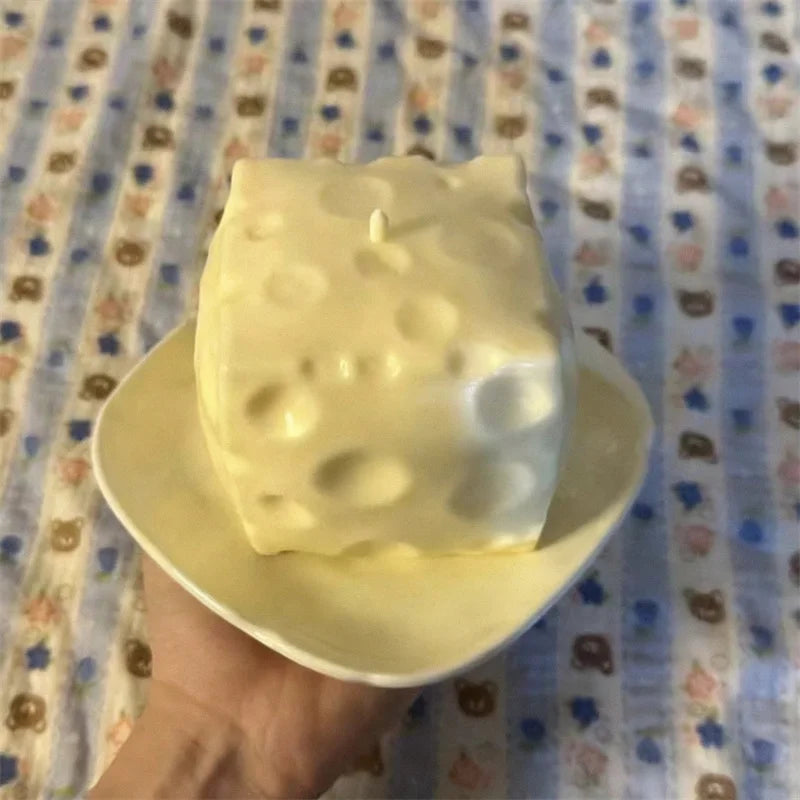 Hand squeezing a large cheese cube stress ball to show compressibility.