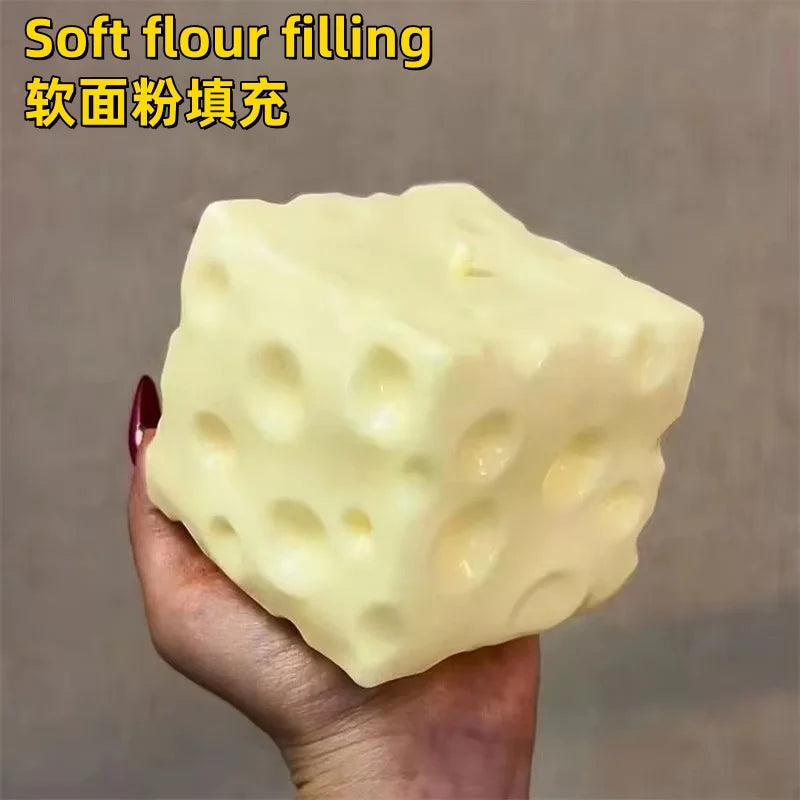 Cheese-cube stress ball shown with other small fidget toys for scale.