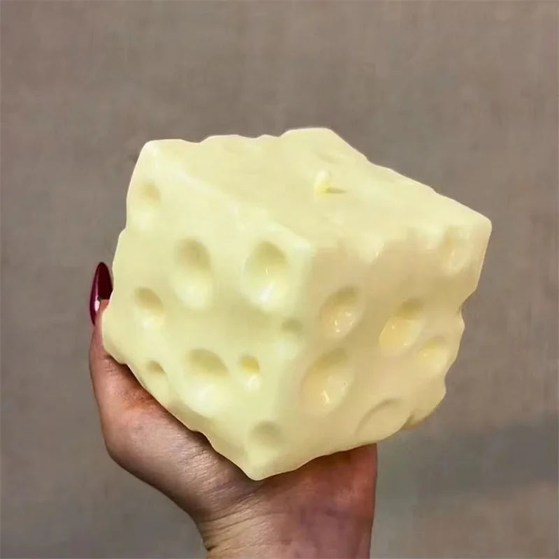 Jumbo cheese cube stress ball shown squished in a hand as a fidget toy.